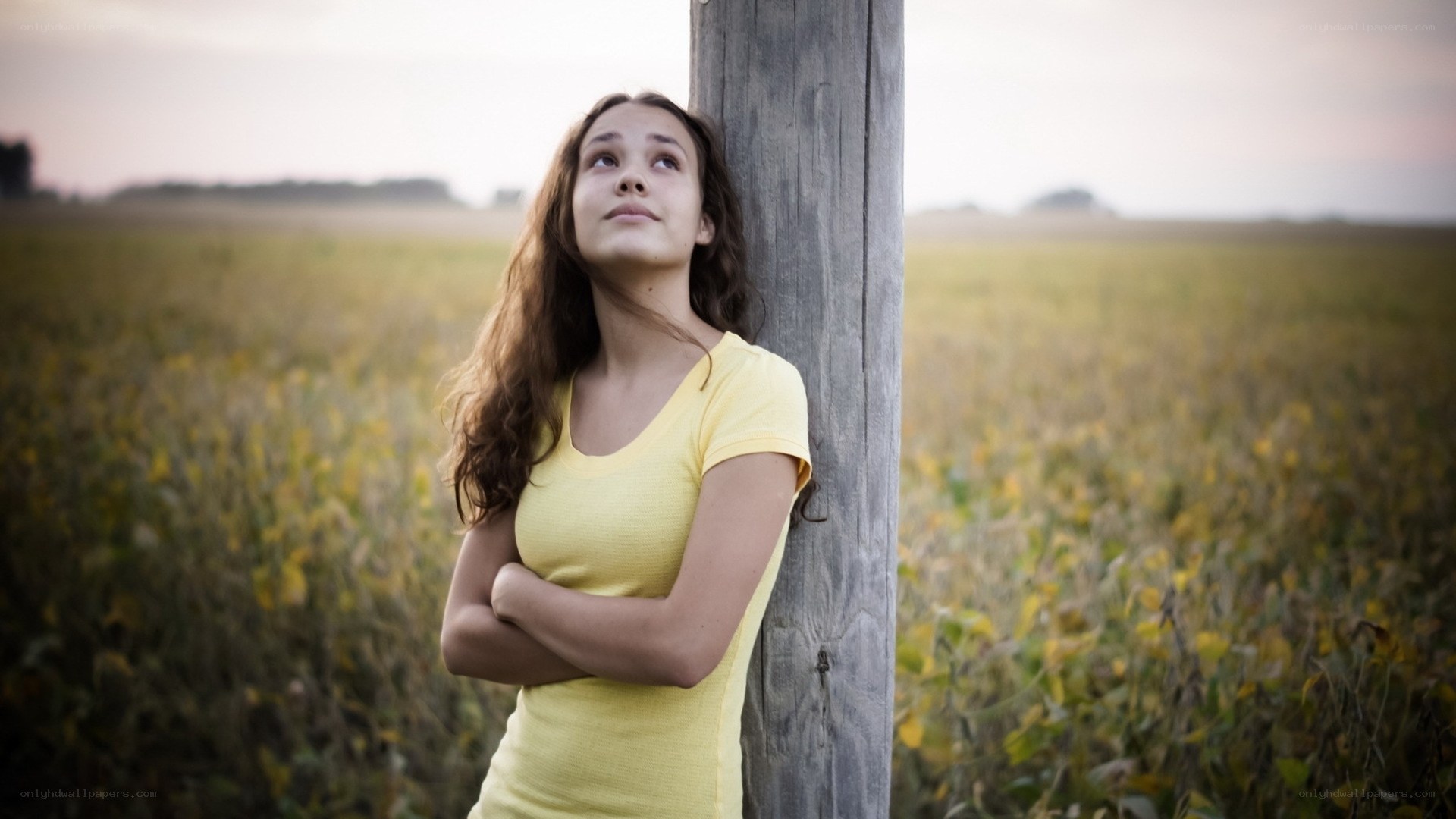 Girl leaning on post in field