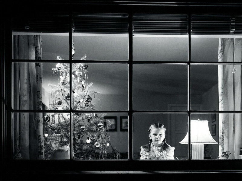 girl looking out window at christmas tree