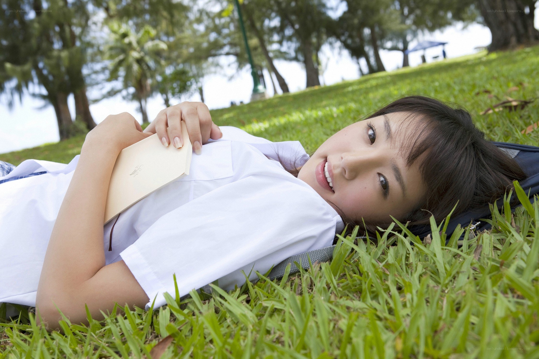 Girl lying on grass with book