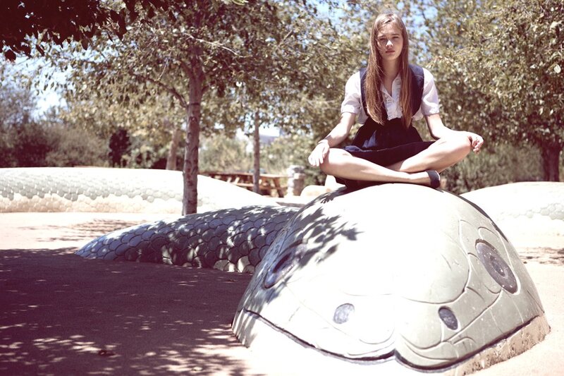 Girl meditating on snake sculpture