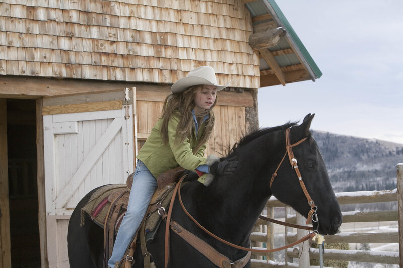 Girl on a horse near barn