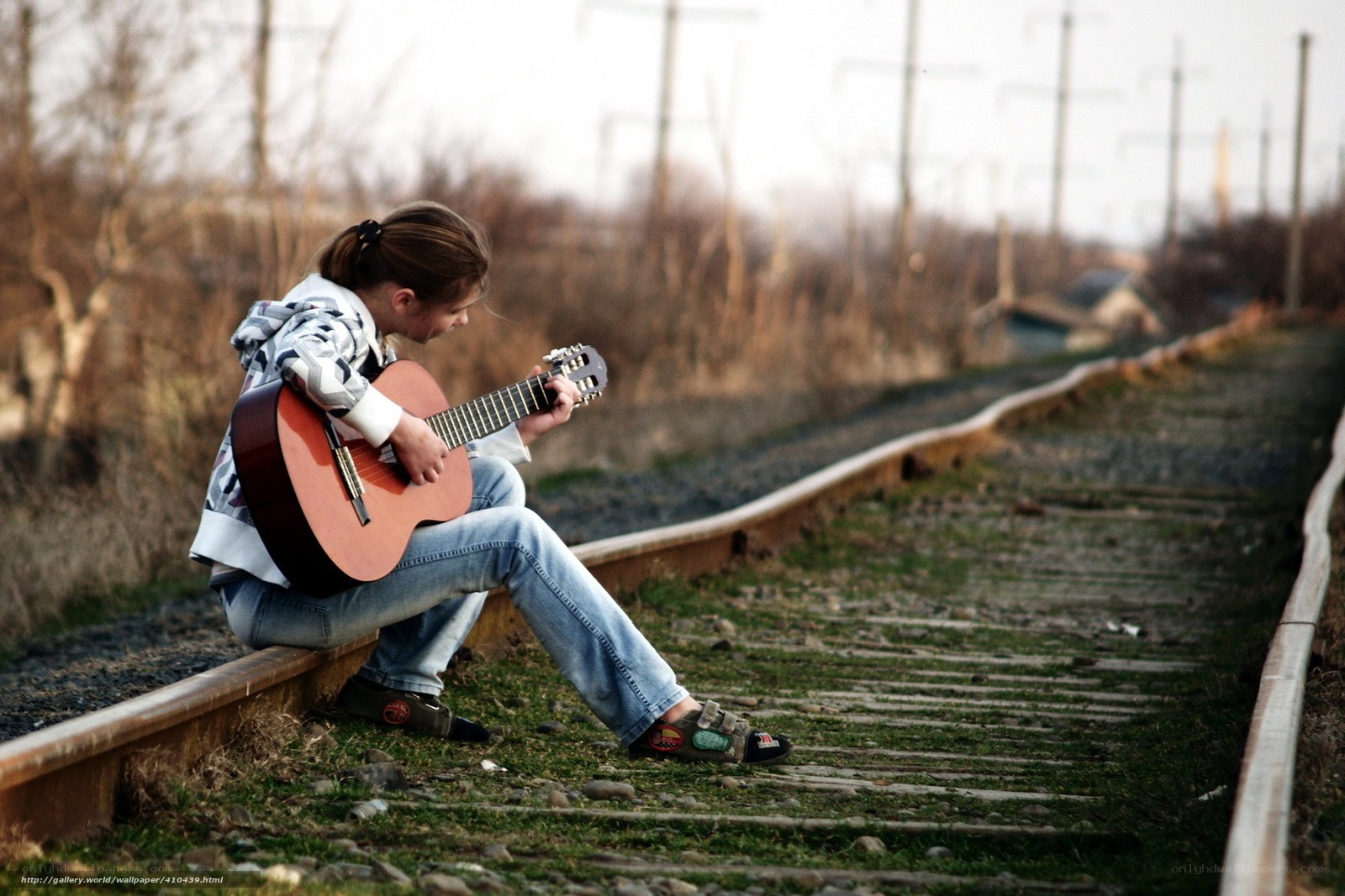 Girl playing guitar on train tracks