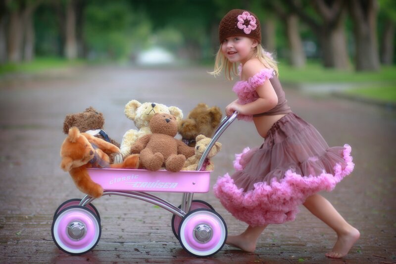 girl pushing wagon with teddy bears