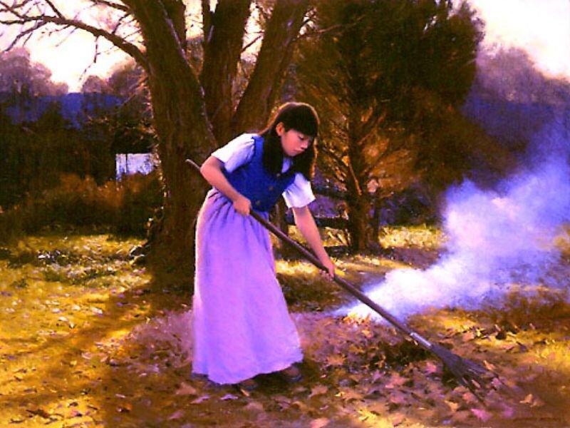Girl raking leaves in a field