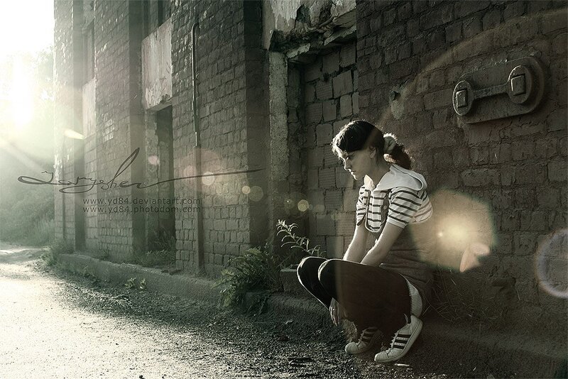 Girl sitting by a brick wall