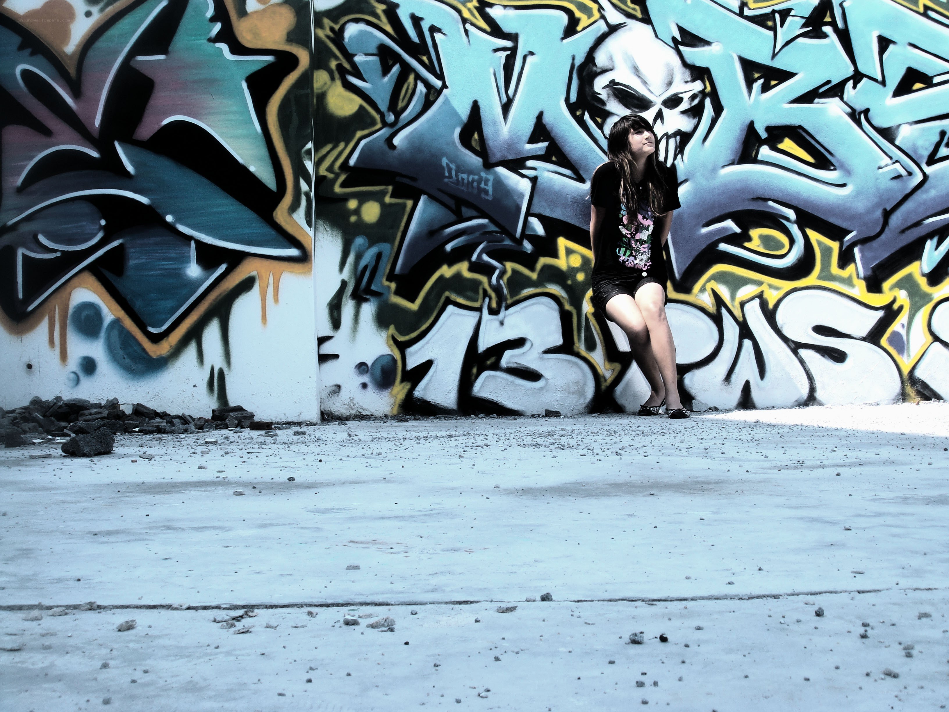 Girl sitting by graffiti wall