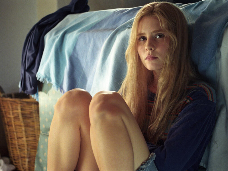 girl sitting on bed looking sad