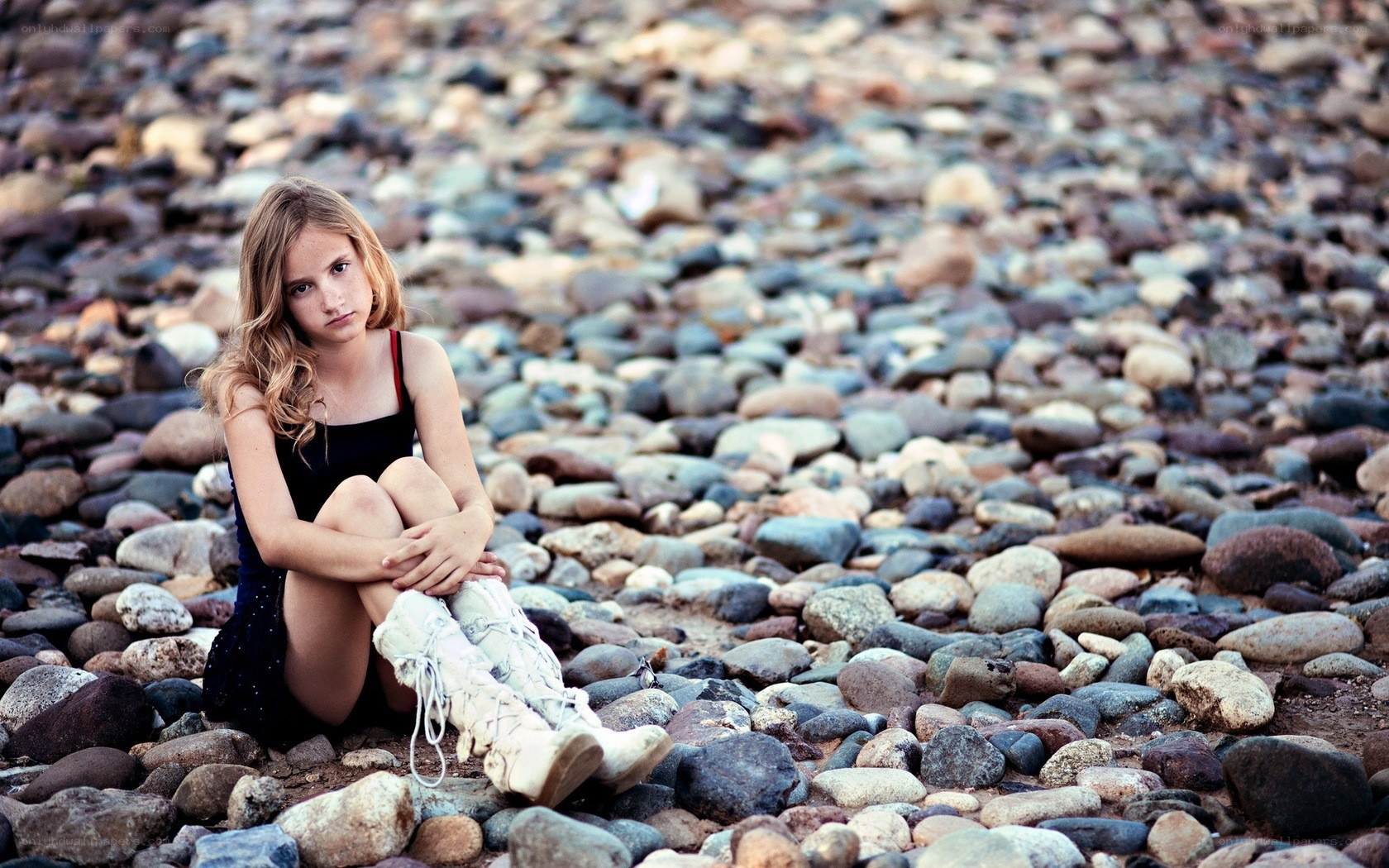 girl sitting on pebbles