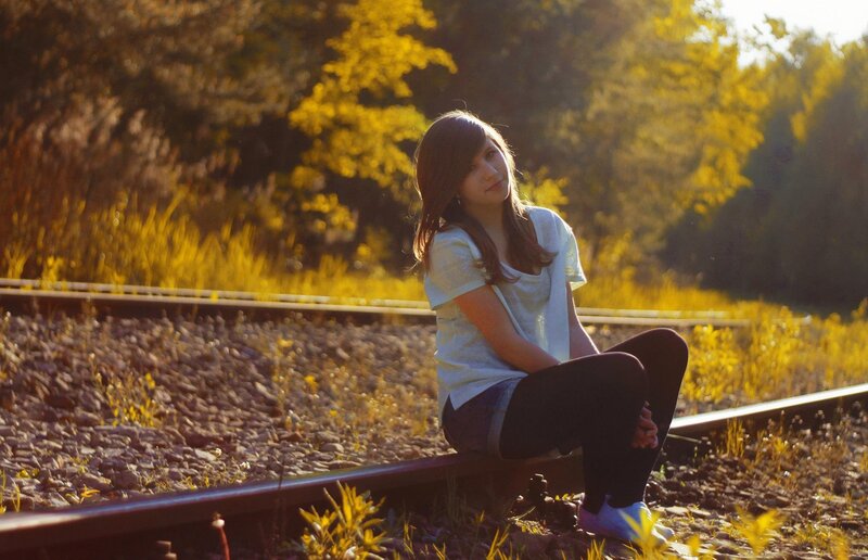 Girl sitting on train tracks