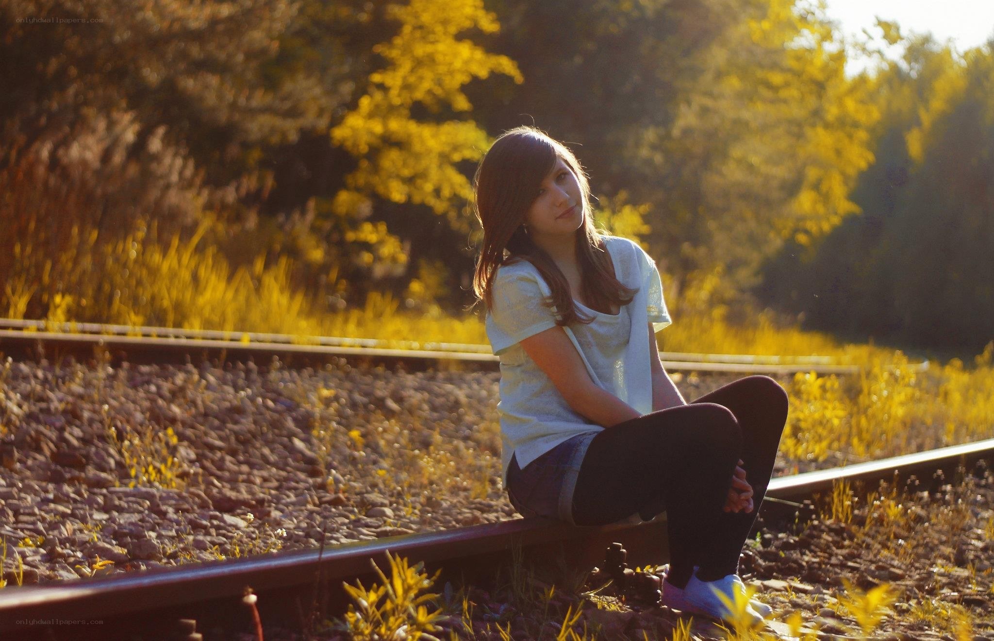 Girl sitting on train tracks