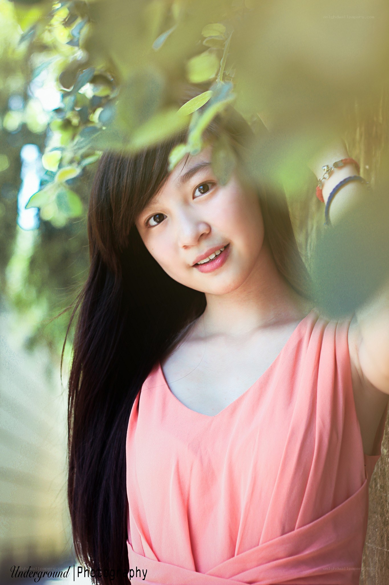 girl smiling behind leaves