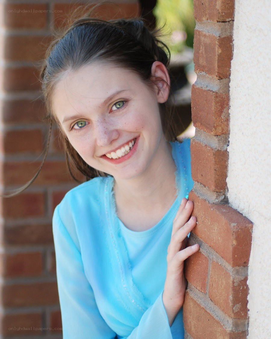 girl smiling by brick wall