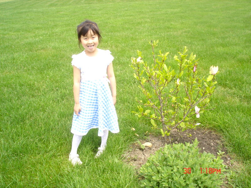 girl standing by a flowering bush