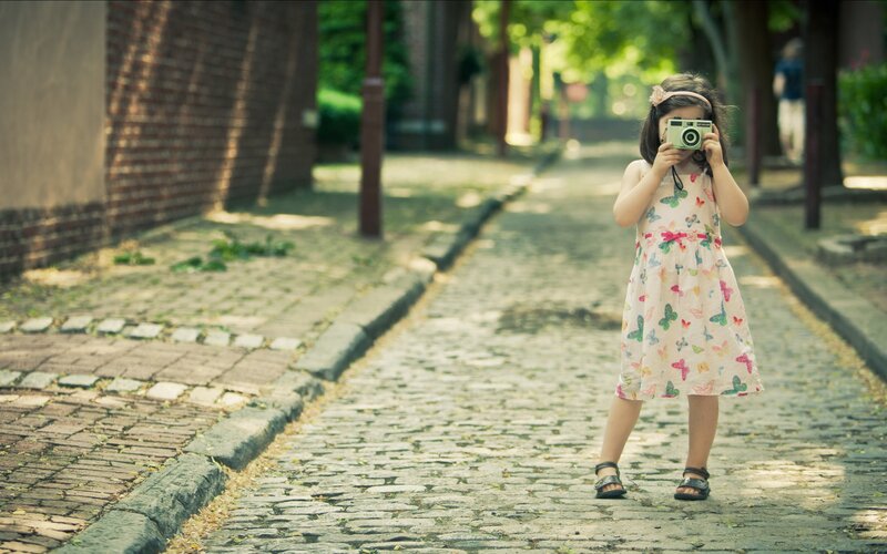 Girl taking a photo on cobblestones