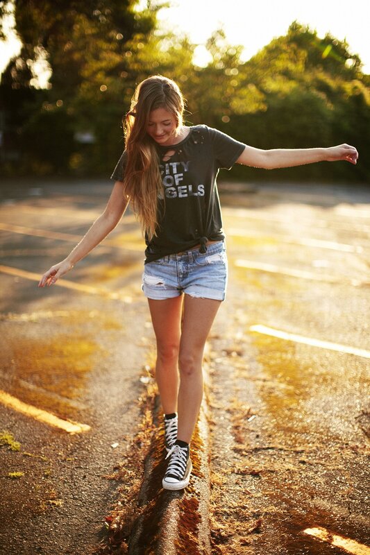 Girl walking on a curb at sunset