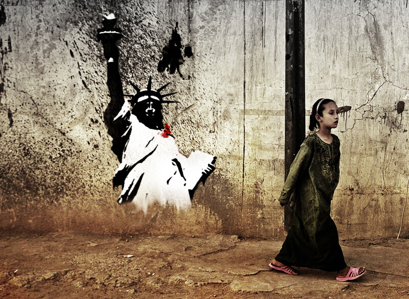 Girl walks past graffiti of Statue of Liberty