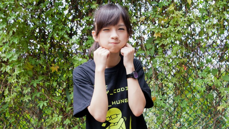 girl winking in front of greenery