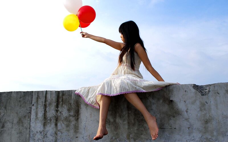 Girl with balloons on wall