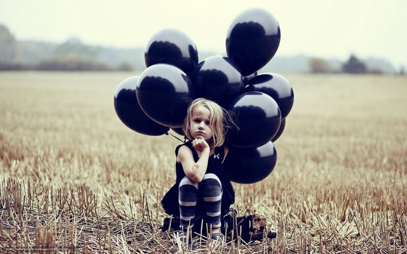 Girl with black balloons in field