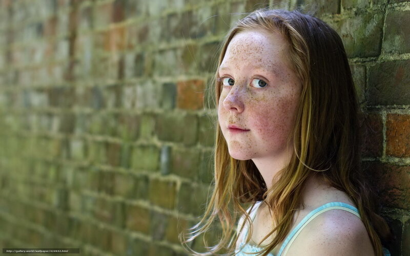 girl with freckles against brick wall