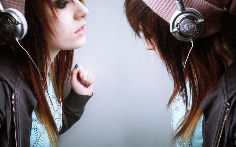 girl with headphones looking at mirror