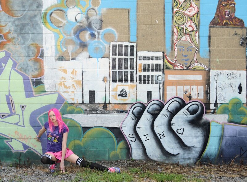 Girl with pink hair in front of graffiti