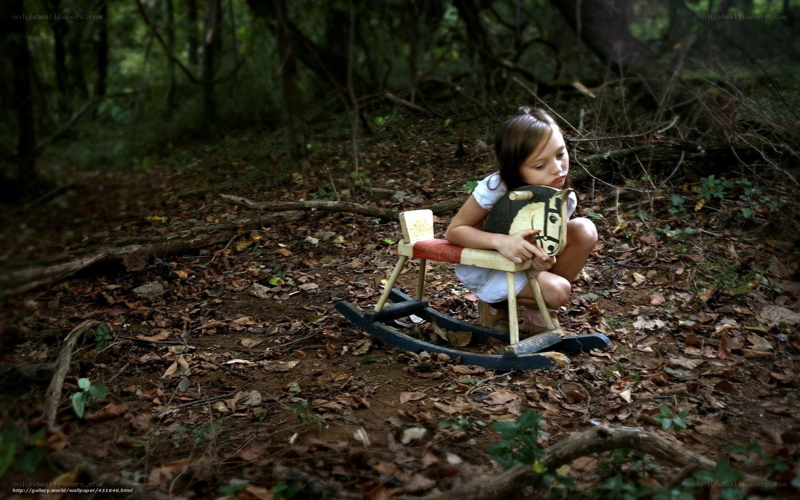 Girl with rocking horse in forest