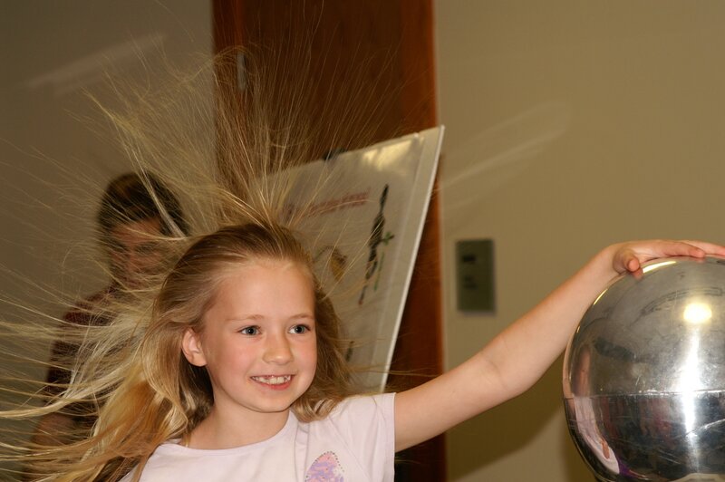 Girl with static hair from metal sphere