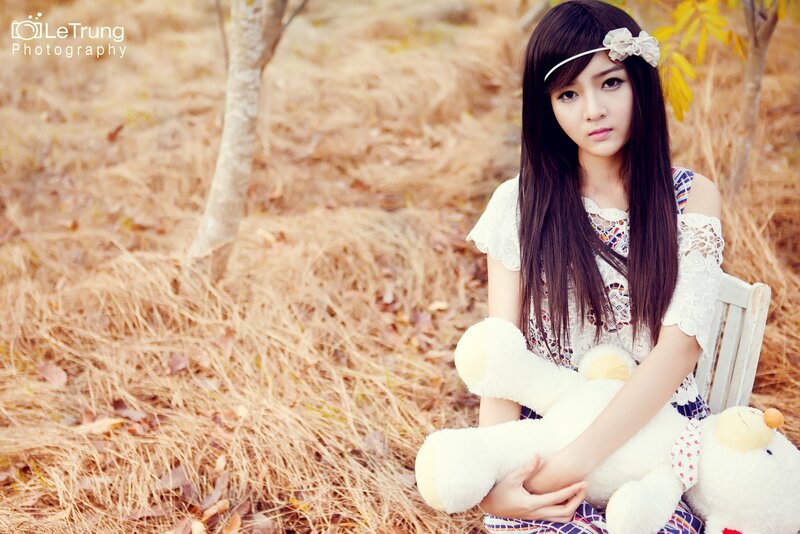 girl with teddy bear in field