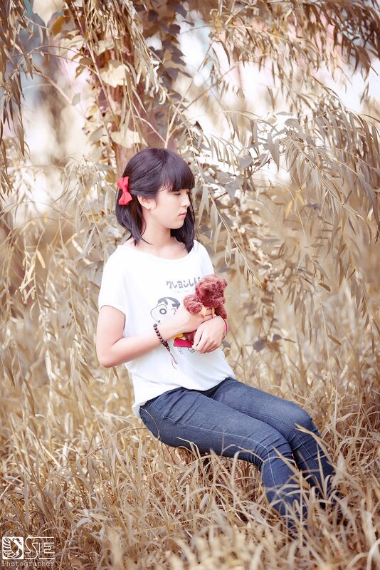 Girl with teddy bear in field