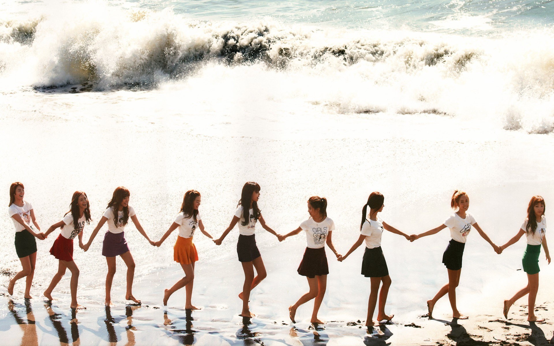 girls holding hands on beach