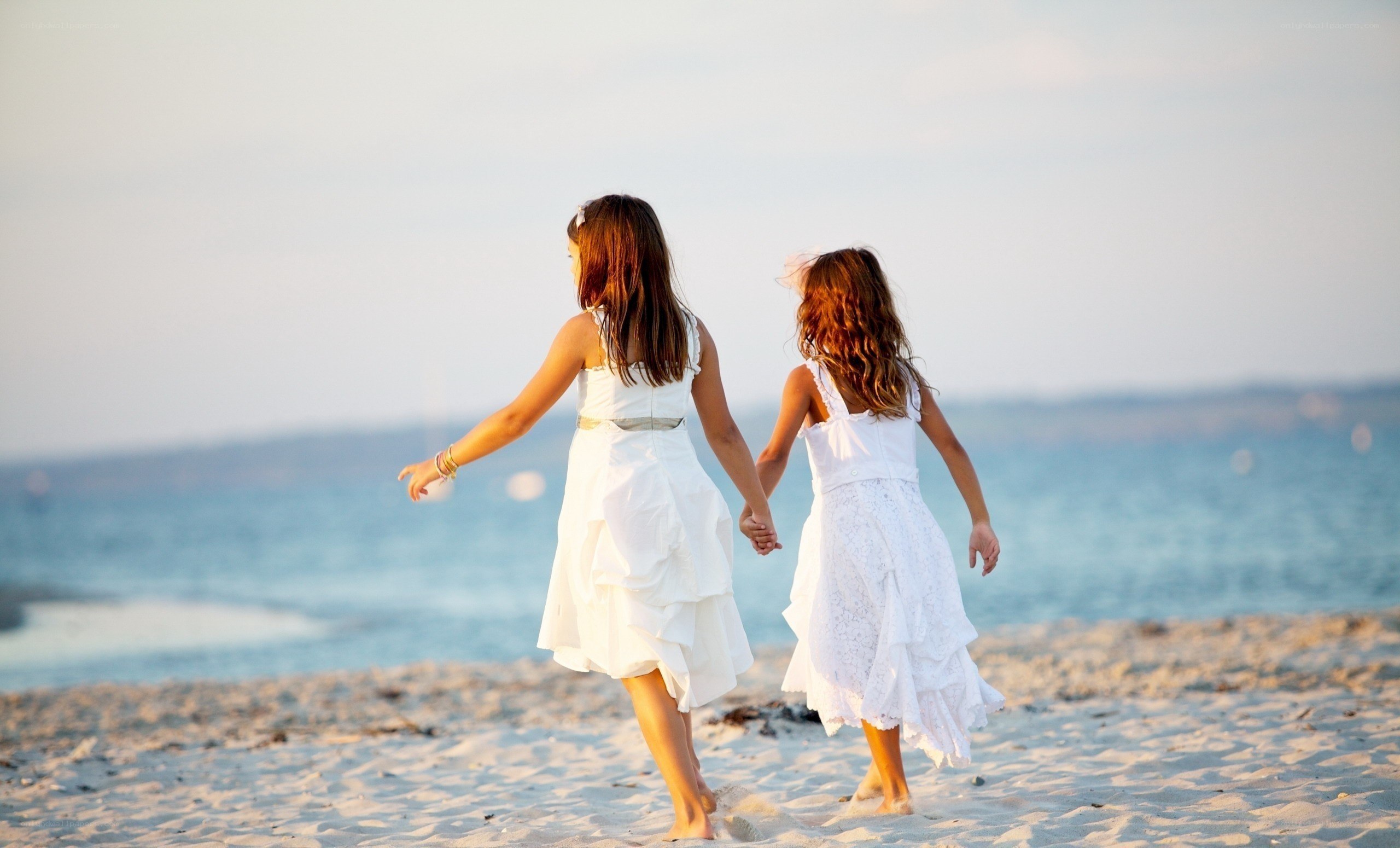 girls holding hands on beach