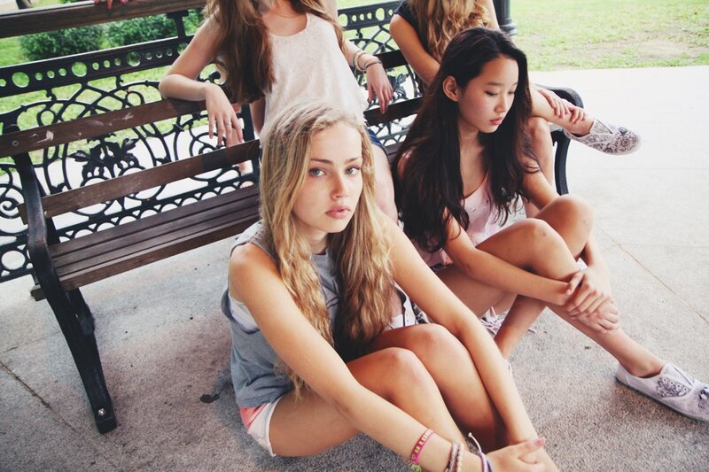 girls sitting on a park bench