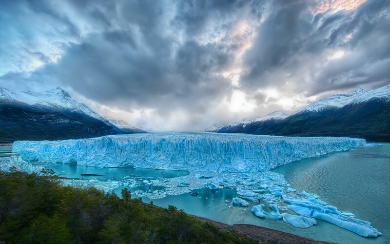 Glacier Calving into Lake — Blue, Dramatic, Sunset, Photograph, Mountains, Icebergs, Clouds, White, Green