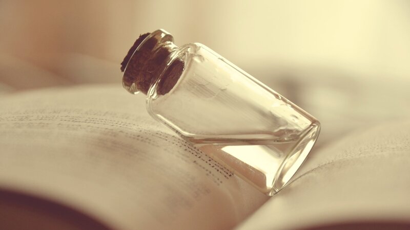 glass bottle on open book