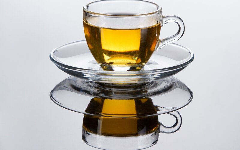 Glass cup of tea on saucer
