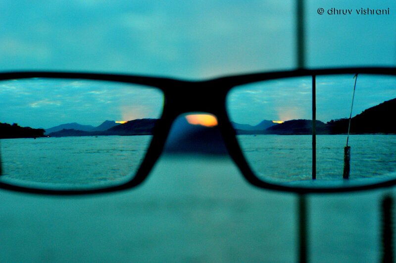 glasses view of sunset over water