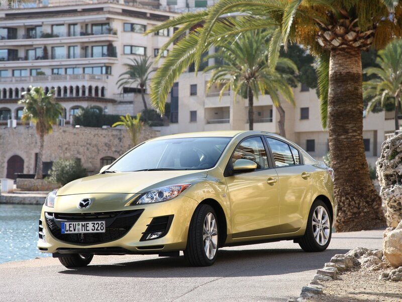 Gold Mazda 3 sedan by the water