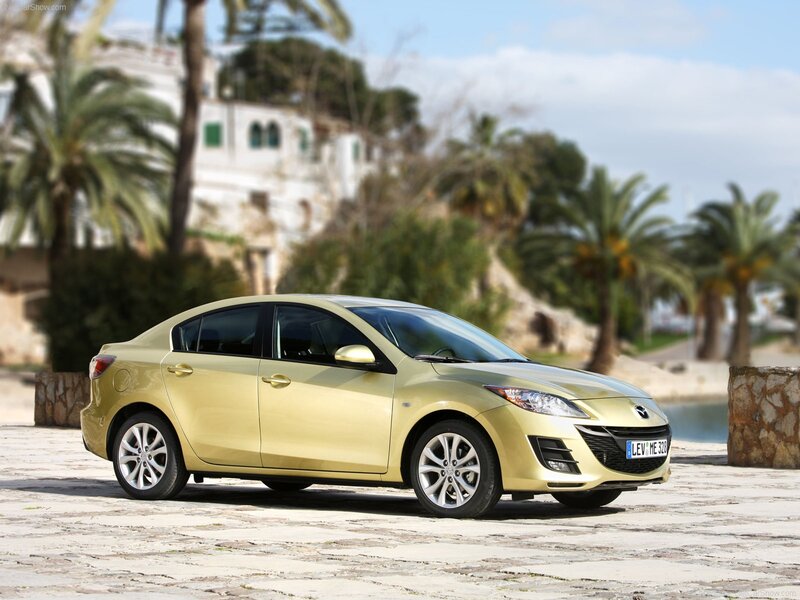 gold mazda3 sedan on cobblestone