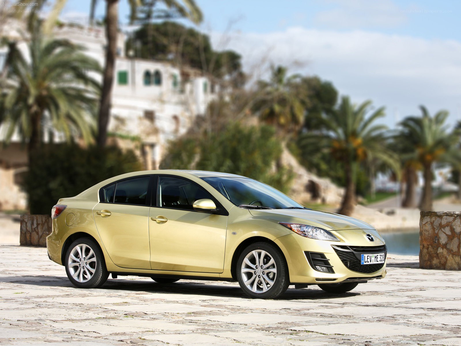 gold mazda3 sedan on cobblestone
