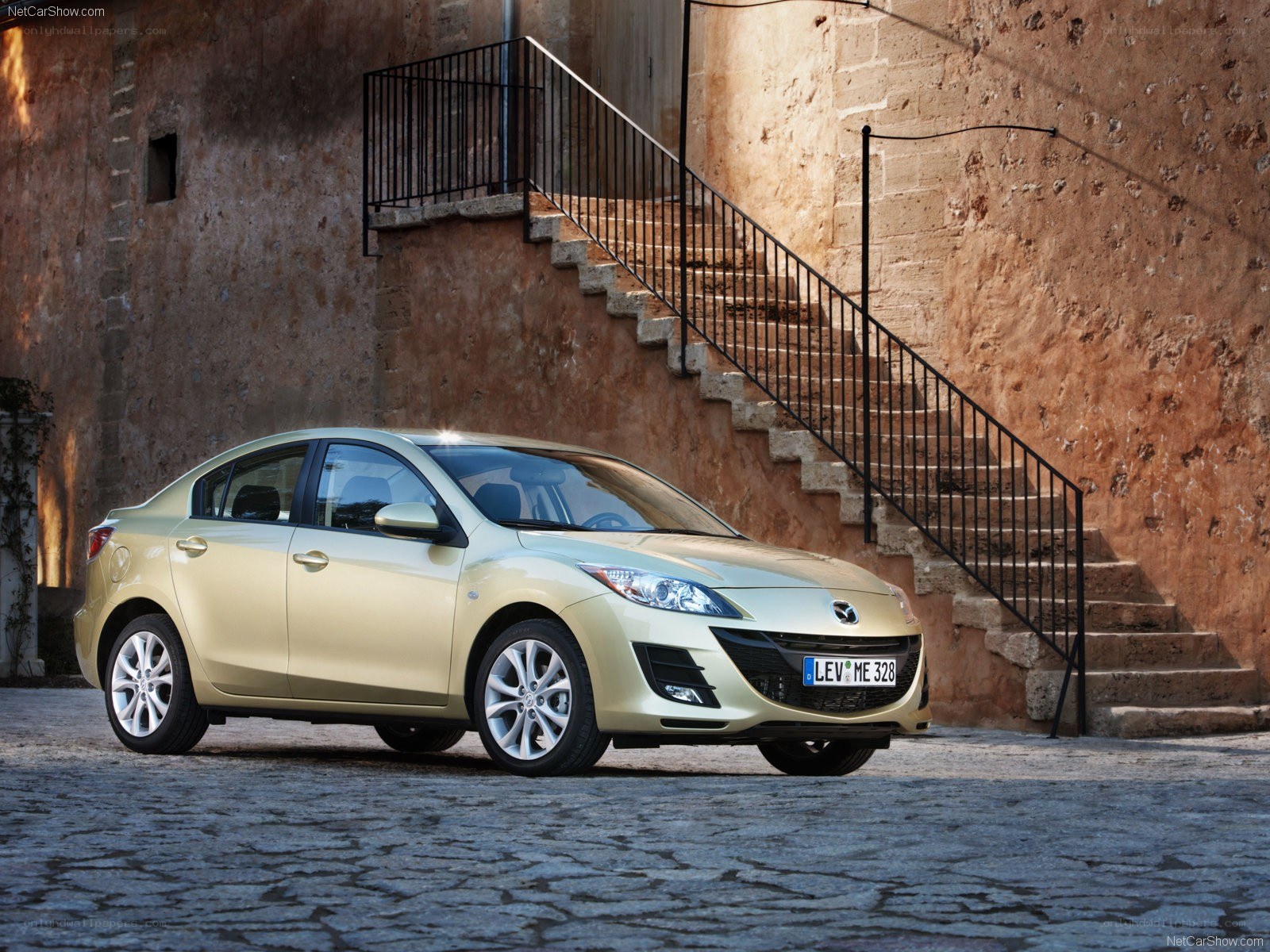 gold mazda3 sedan on cobblestone
