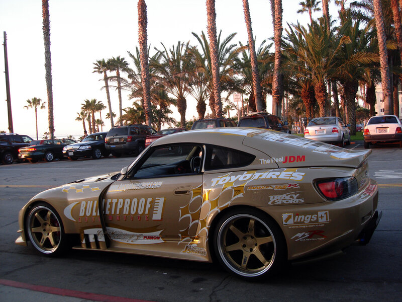 gold race car on palm-lined street