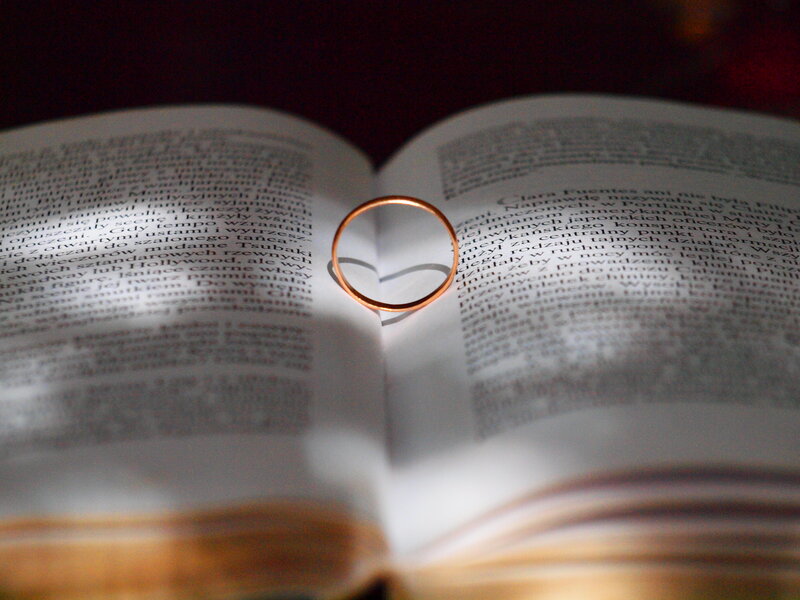 Gold Wedding Ring on Book — White