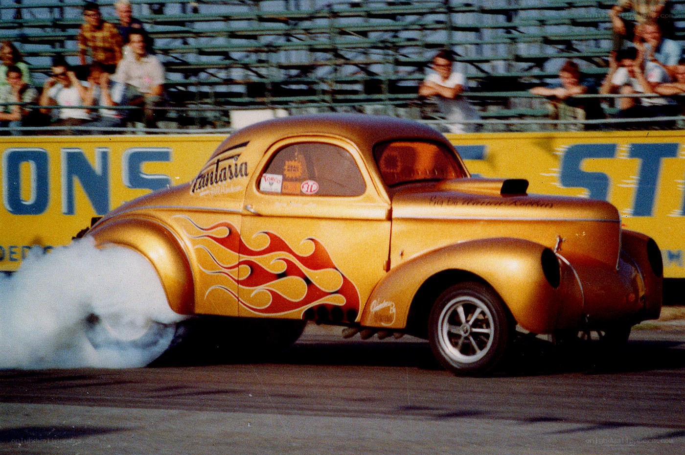 Golden drag car performing burnout