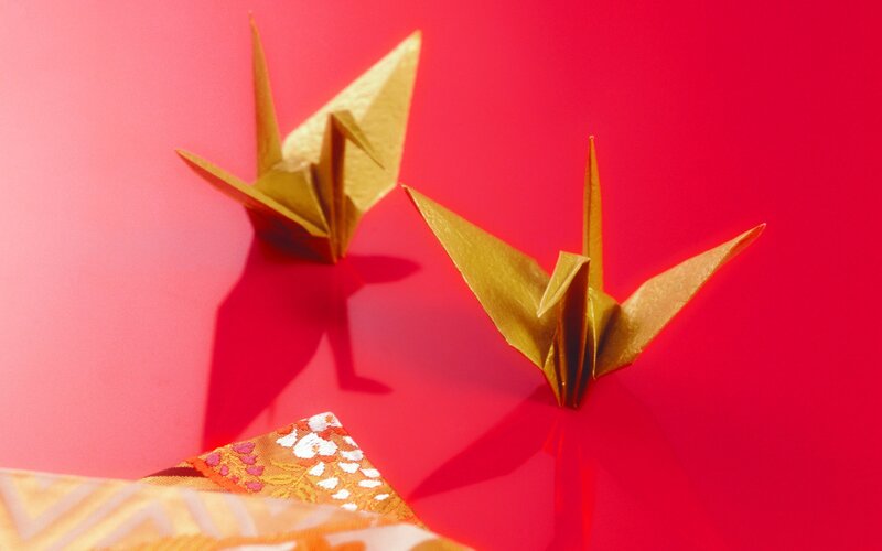 Golden origami cranes on red