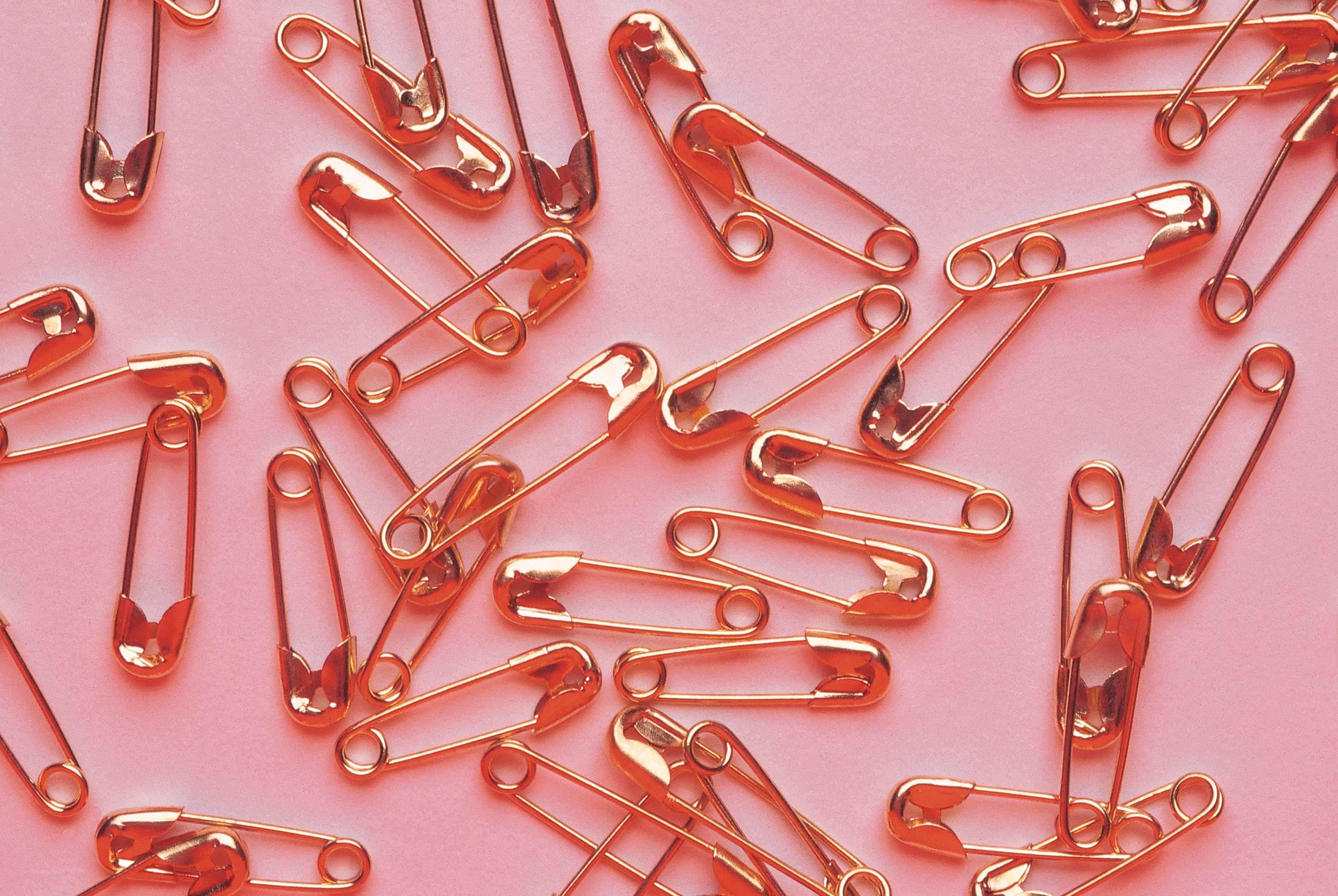 golden safety pins on pink
