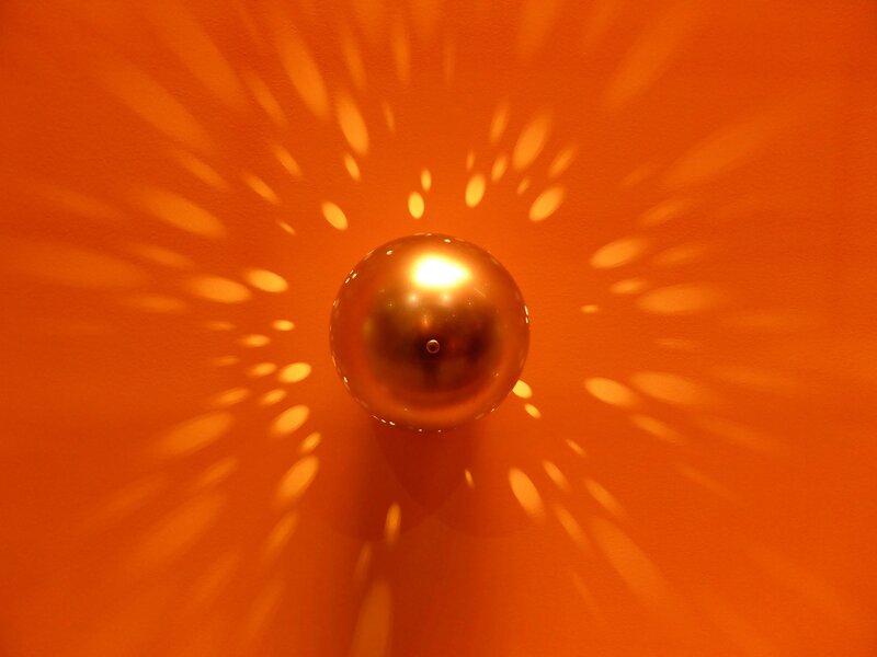 Golden sphere on orange wall