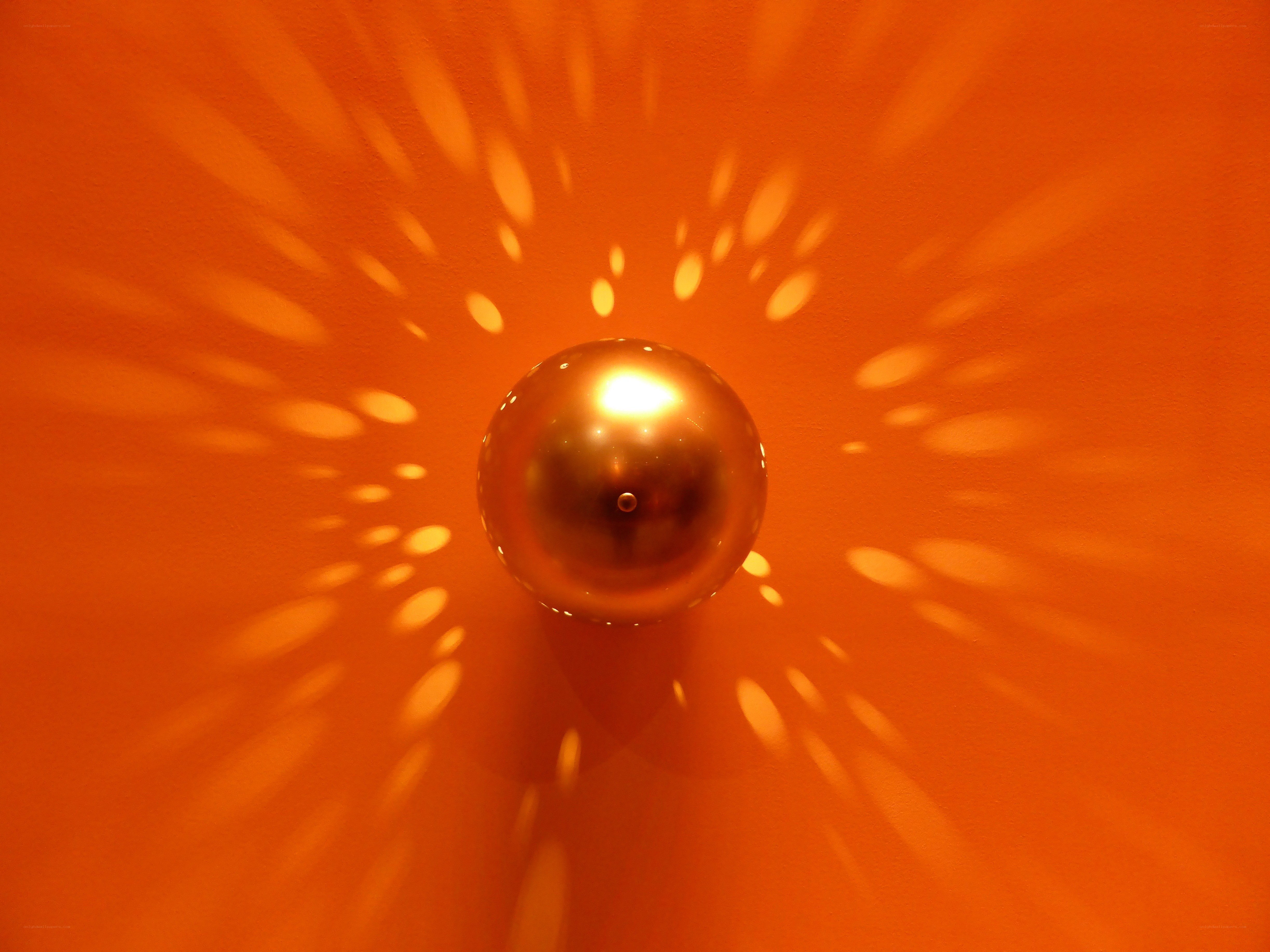 Golden sphere on orange wall