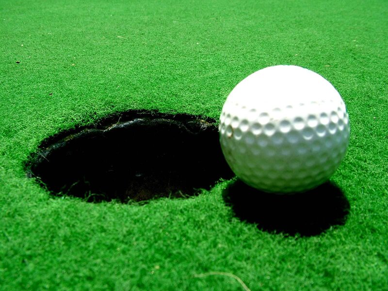 golf ball near hole on green