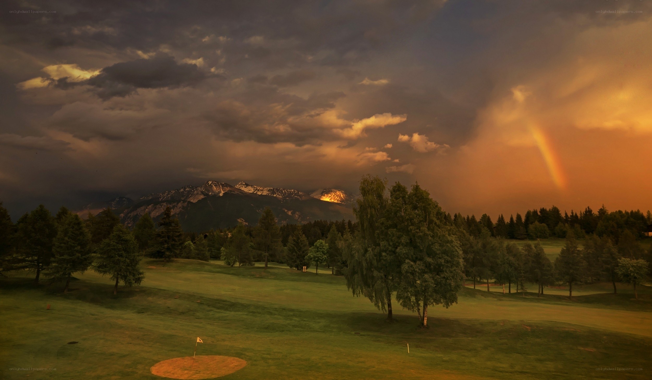 Golf course with rainbow and mountains